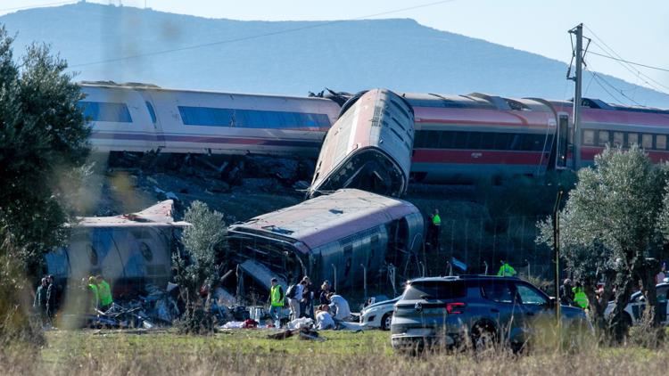 Rescue workers at the scene of a train derailment in Spain, with emergency vehicles and debris visible.